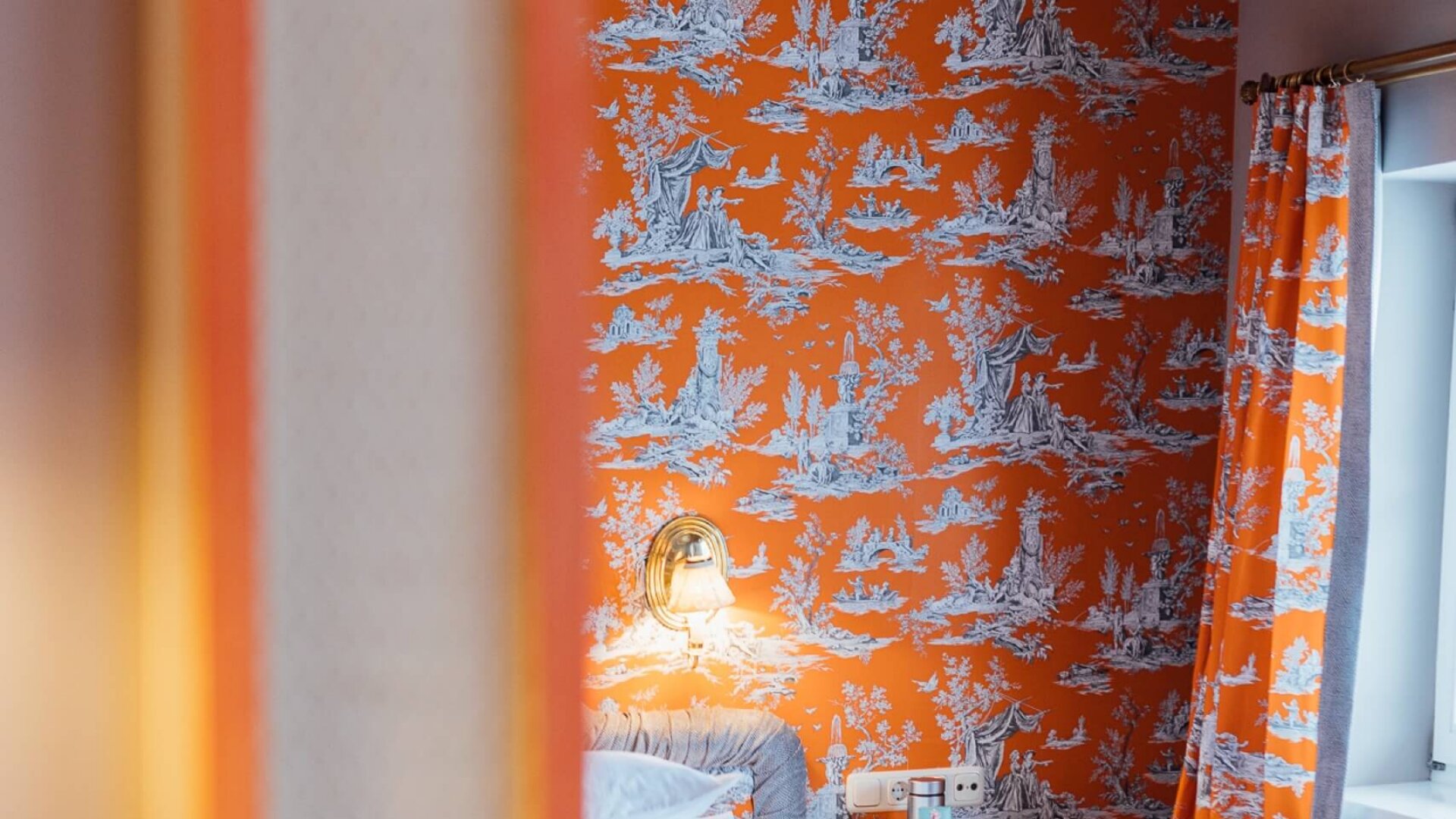 Blick in ein stilvolles Hotelzimmer im Hotel Edelweiss, geprägt von orangefarbenen Wänden und gemütlicher Einrichtung.