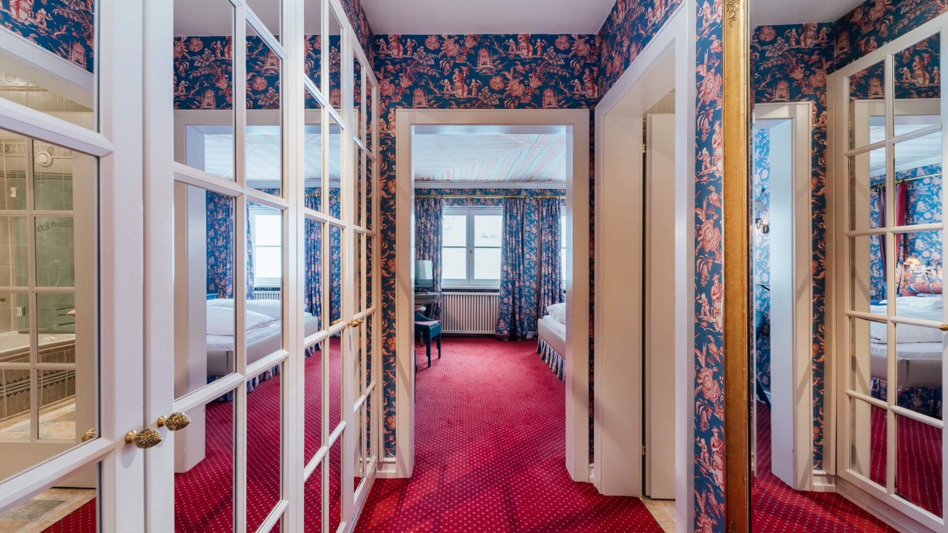 Gemütlicher Hotelflur im Hotel Edelweiss mit buntem Tapetenmuster und spiegelnden Türen in Lech/Zürs.