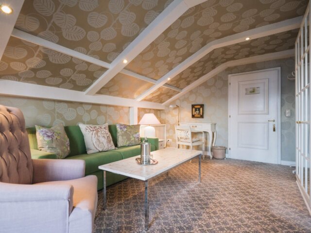 Gemütliches Zimmer im Hotel Edelweiss mit modernem Design, grünem Sofa und eleganter Einrichtung in Lech/Zürs am Arlberg.