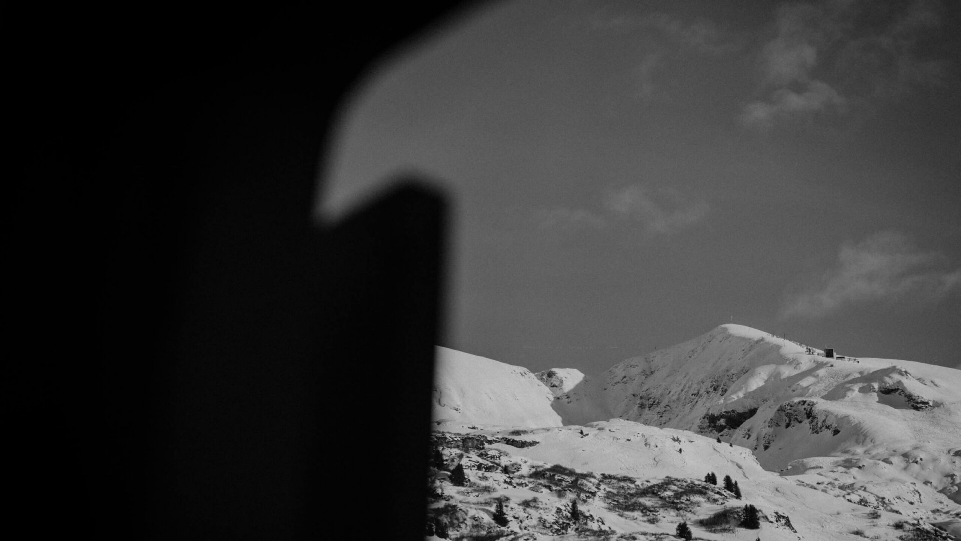 Aussicht auf verschneite Berge in Lech/Zürs, eingefangen durch einen Fensterrahmen des Hotels Edelweiss.