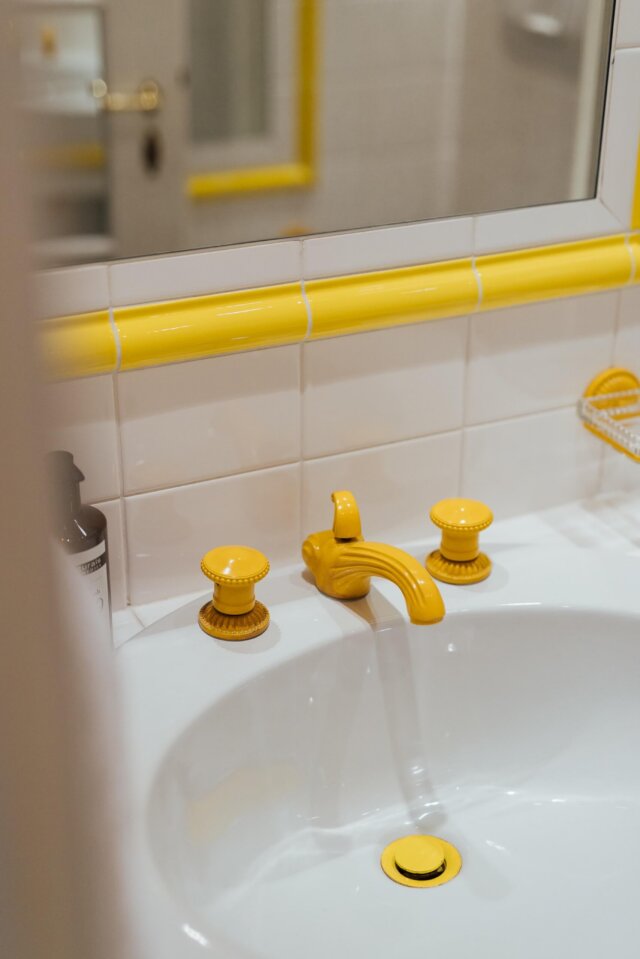 Badezimmer mit stilvollen gelben Armaturen im Hotel Edelweiss, Lech/Zürs am Arlberg. Entspannung und Eleganz vereint.