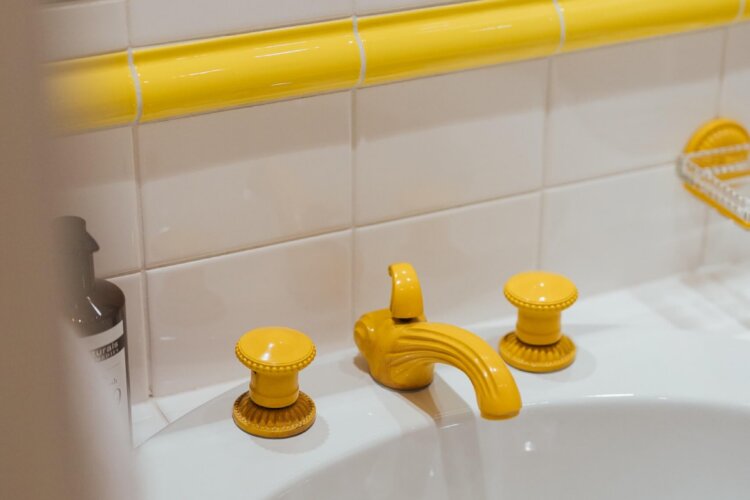 Badezimmer mit stilvollen gelben Armaturen im Hotel Edelweiss, Lech/Zürs am Arlberg. Entspannung und Eleganz vereint.
