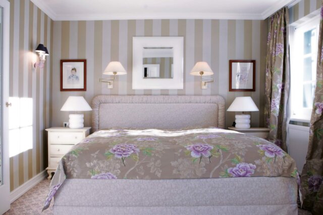 Gemütliches Schlafzimmer im Hotel Edelweiss in Lech/Zürs mit floralem Bettüberwurf und eleganter Ausstattung.