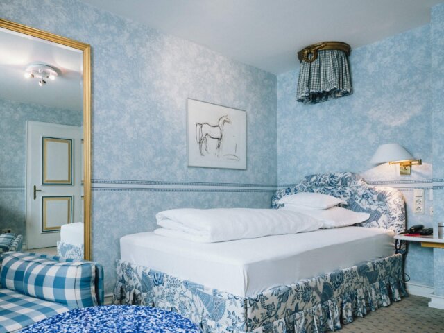 Gemütliches Hotelzimmer im Hotel Edelweiss, Lech/Zürs, mit elegantem Interieur in Blau und Weiß.