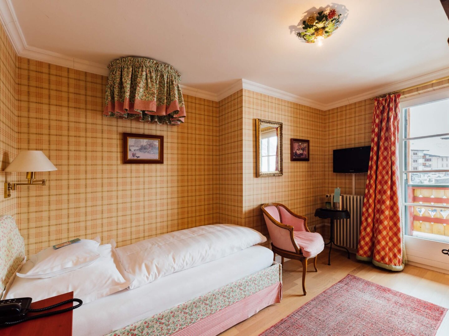 Gemütliches Hotelzimmer im Hotel Edelweiss in Lech/Zürs mit traditionellem Dekor und Balkonblick.