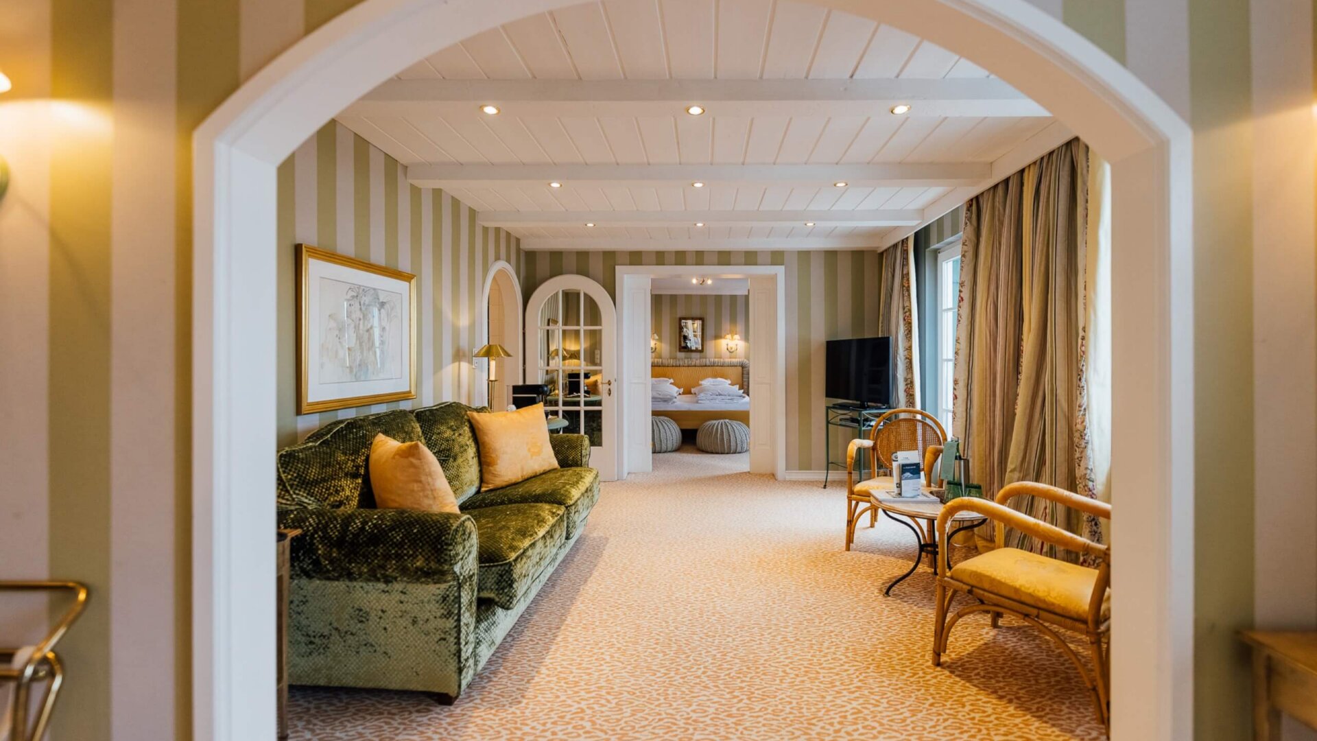 Stilvolles Zimmer im Hotel Edelweiss mit gemütlichem Sofa und Blick auf den Schlafbereich in Lech/Zürs.