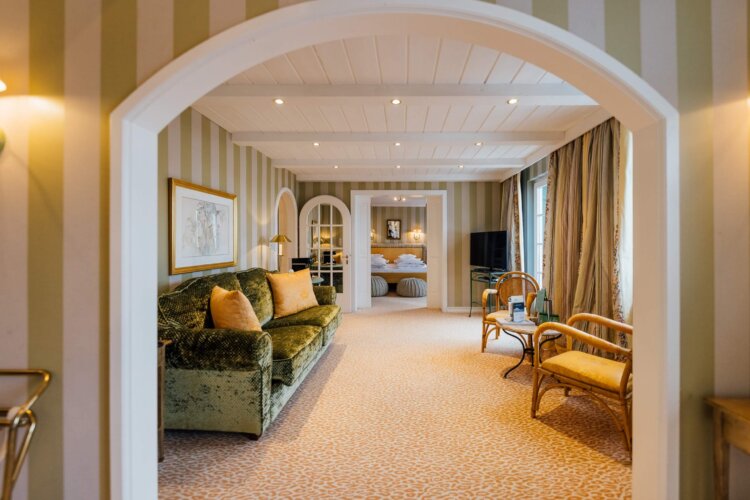 Stilvolles Zimmer im Hotel Edelweiss mit gemütlichem Sofa und Blick auf den Schlafbereich in Lech/Zürs.