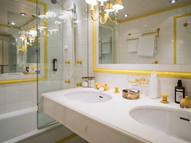 Stilvolles Badezimmer im Hotel Edelweiss mit eleganter Ausstattung in Gelb- und Weißtönen. Entspannen und wohlfühlen!