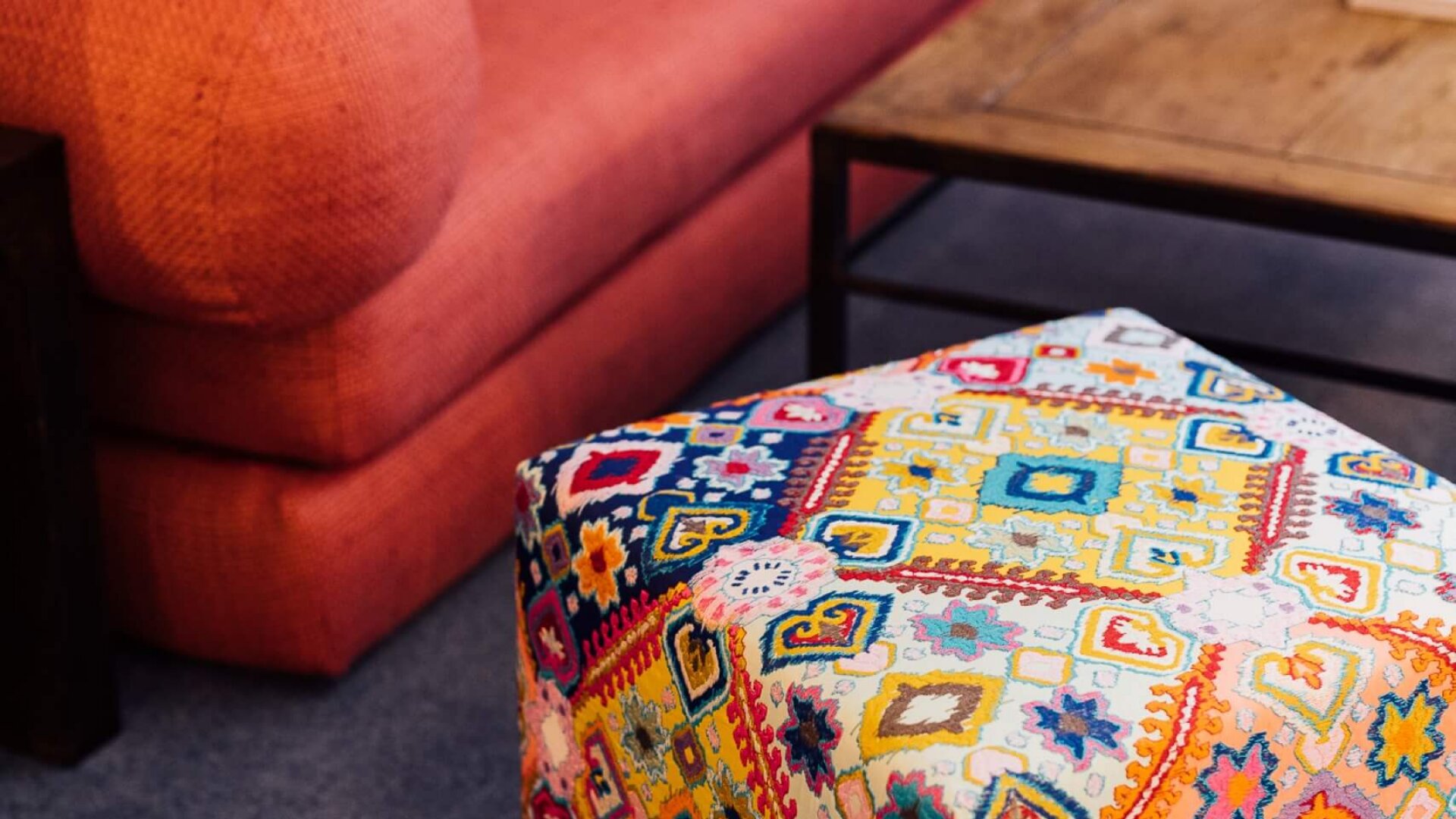 Bequeme Wohnatmosphäre im Hotel Edelweiss: stylisches Sofa und bunter Pouf im gemütlichen Aufenthaltsraum.
