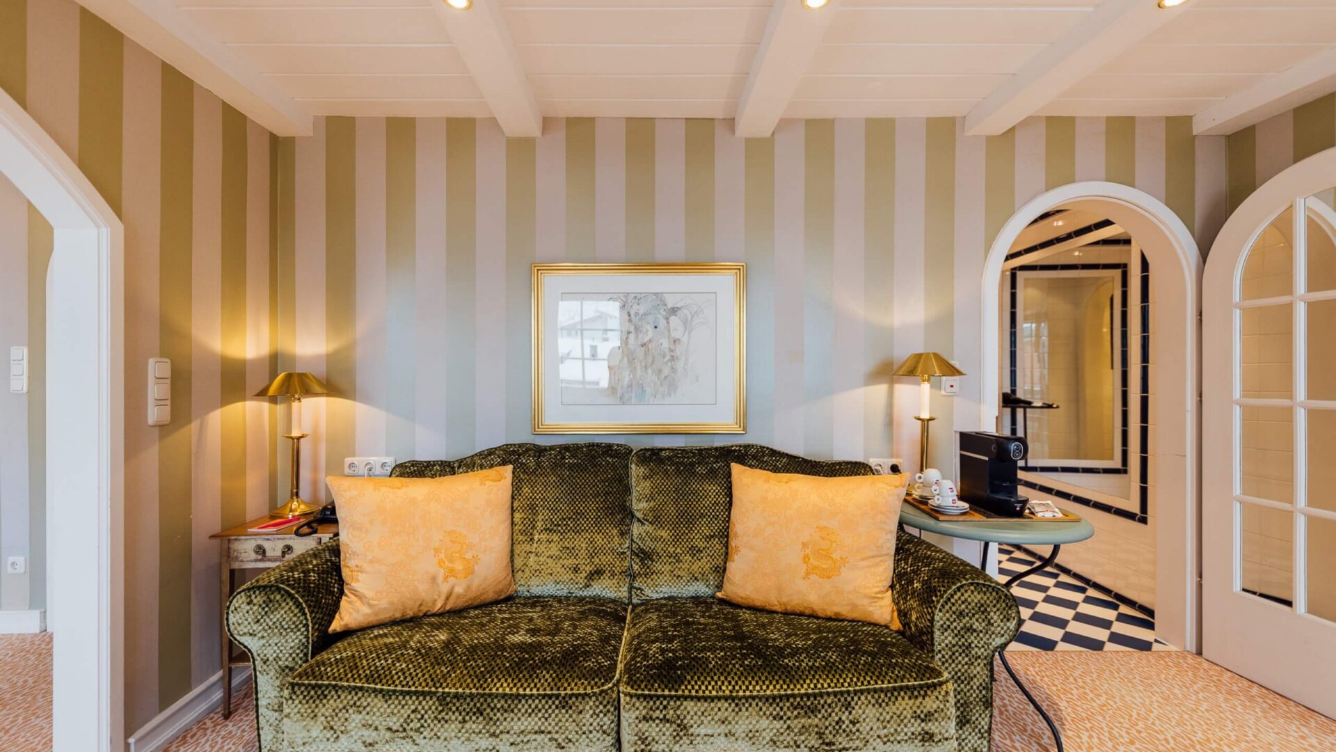 Gemütliche Hotelzimmer im Hotel Edelweiss mit eleganter Ausstattung, grüner Couch und stilvollem Interieur in Lech/Zürs.