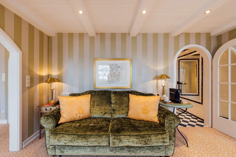 Gemütliche Hotelzimmer im Hotel Edelweiss mit eleganter Ausstattung, grüner Couch und stilvollem Interieur in Lech/Zürs.