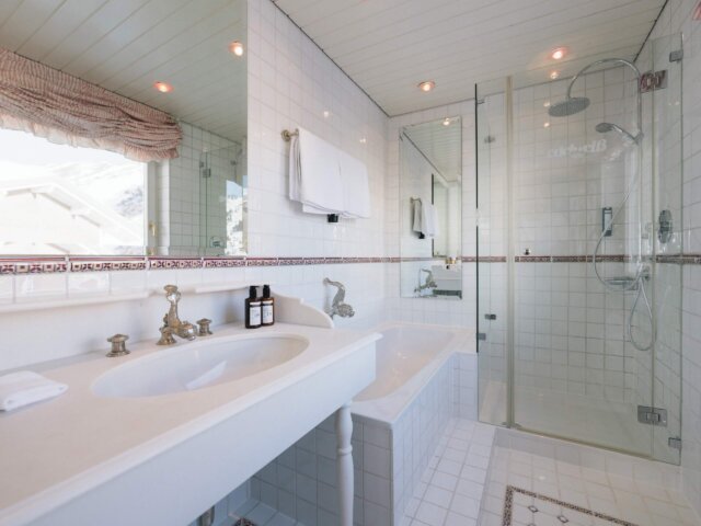 Modernes Badezimmer im Hotel Edelweiss mit eleganter Badewanne, Regendusche und stilvollen Accessoires.
