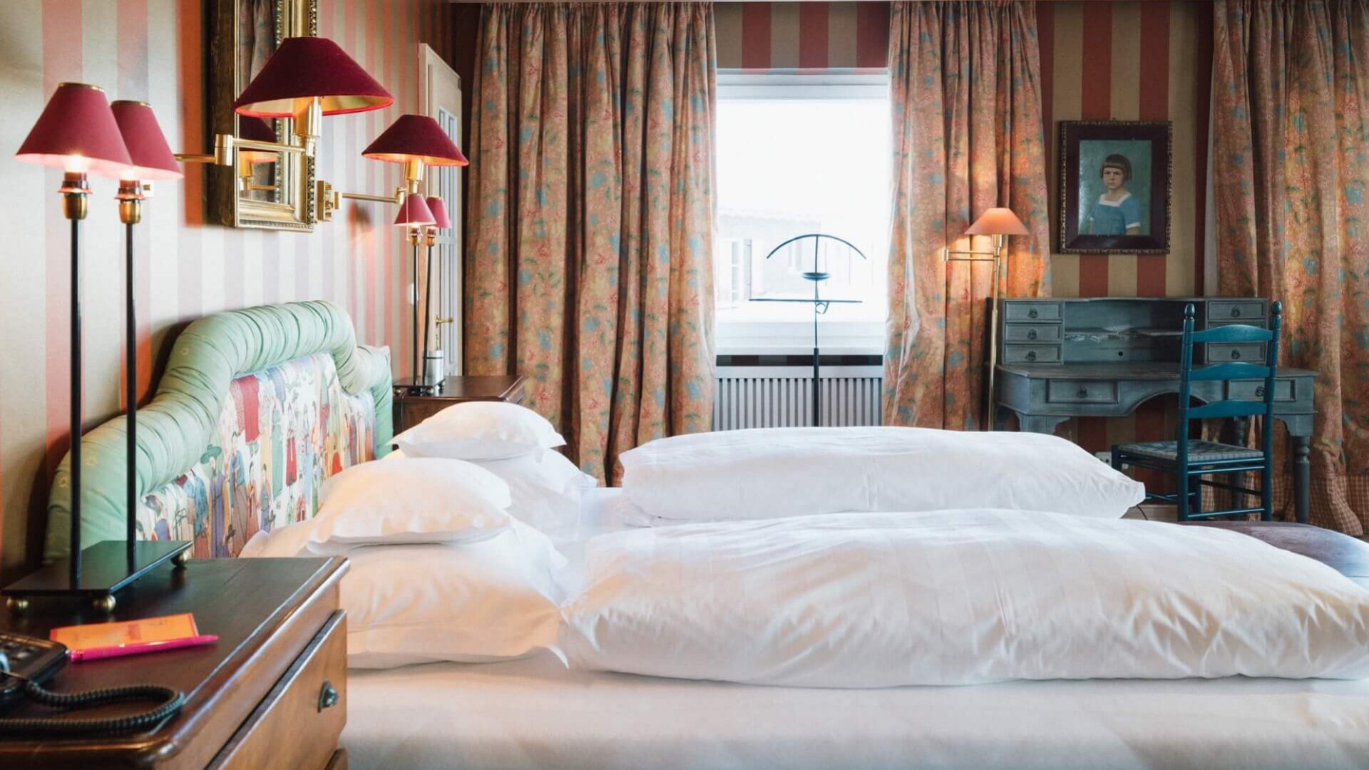 Gemütliches Zimmer im Hotel Edelweiss, Lech/Zürs: stilvolle Einrichtung mit bunten Vorhängen und einem gemütlichen Bett.