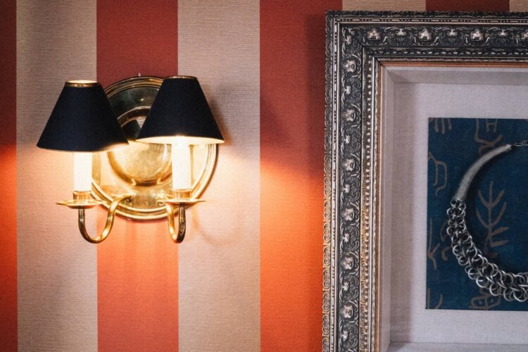 Gemütliche Hotelzimmeratmosphäre im Hotel Edelweiss: elegante Wandleuchte und stilvolles Kunstwerk an rot gestreiften Wänden.