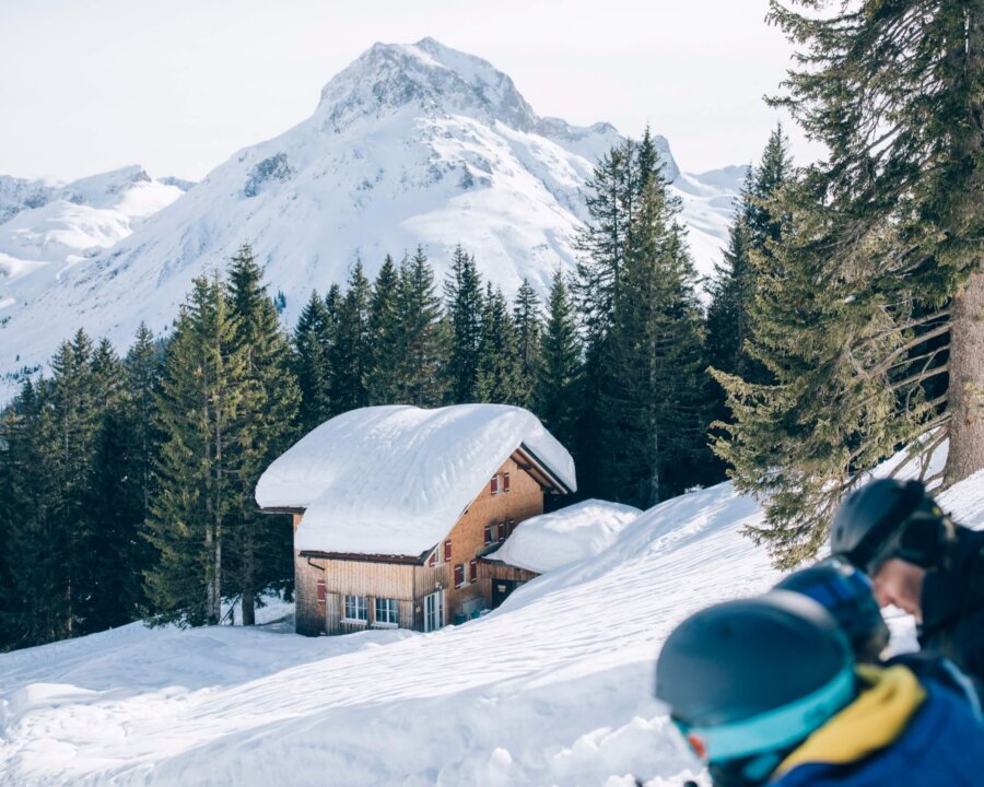 Winterliche Landschaft mit schneebedecktem Haus, umgeben von Bergen und Wäldern in Lech/Zürs am Arlberg.