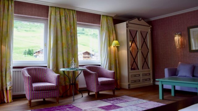 Elegante Hotelzimmer im Hotel Edelweiss mit gemütlichen Sesseln, Blick auf die Berge und stilvollem Interieur in Lech/Zürs.