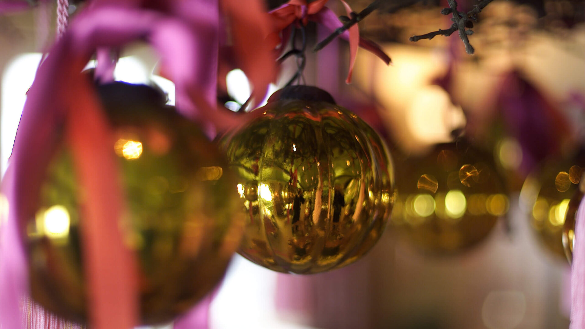 Glänzende goldene Weihnachtskugeln mit pinken Schleifen im festlich dekorierten Hotel Edelweiss in Lech am Arlberg.