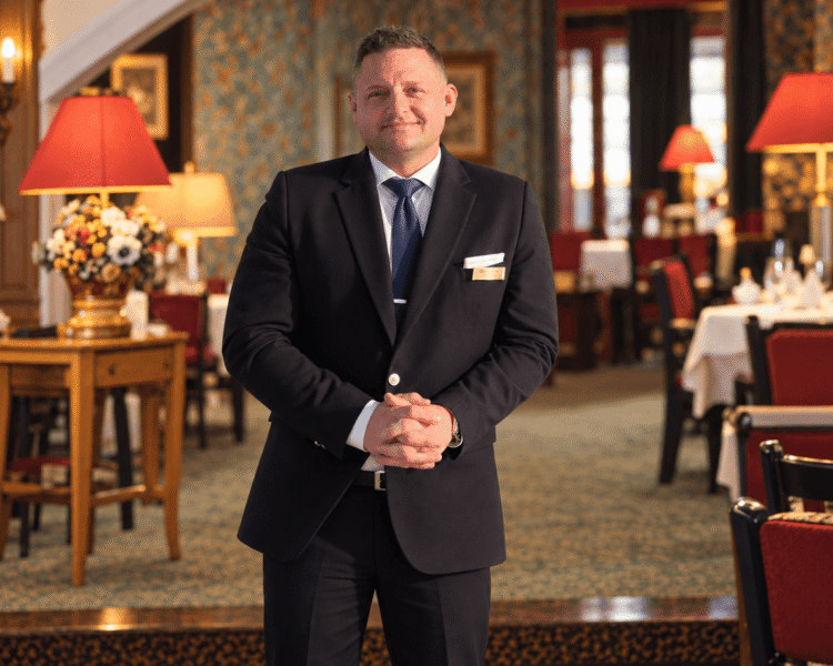 Freundlicher Kellner im eleganten Restaurant des Hotels Edelweiss in Lech/Zürs, bereit, die Gäste zu begrüßen.